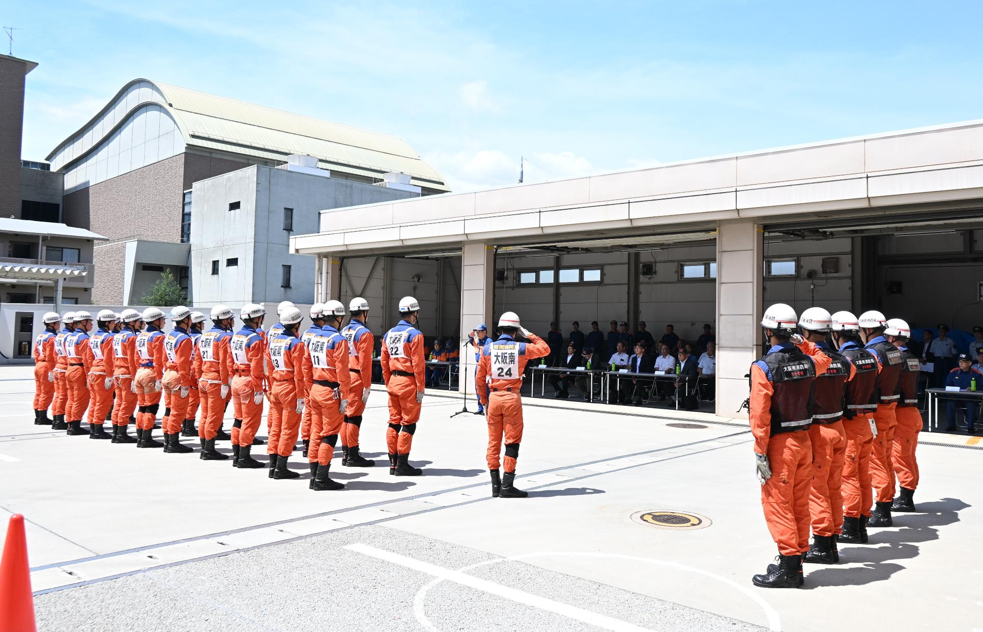消防団長へ整列する救助隊員が敬礼する様子