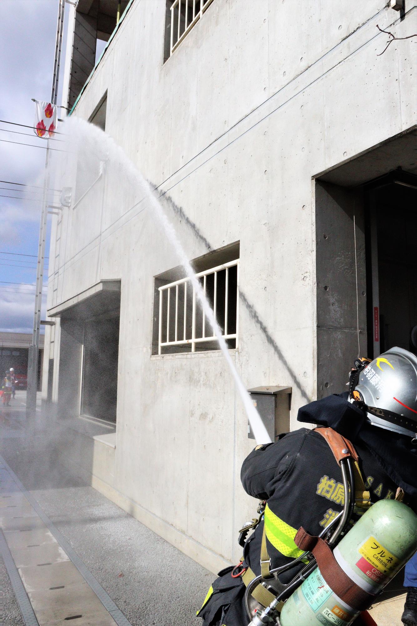 火災建物3階から噴出している火炎に隊員1名が放水している様子