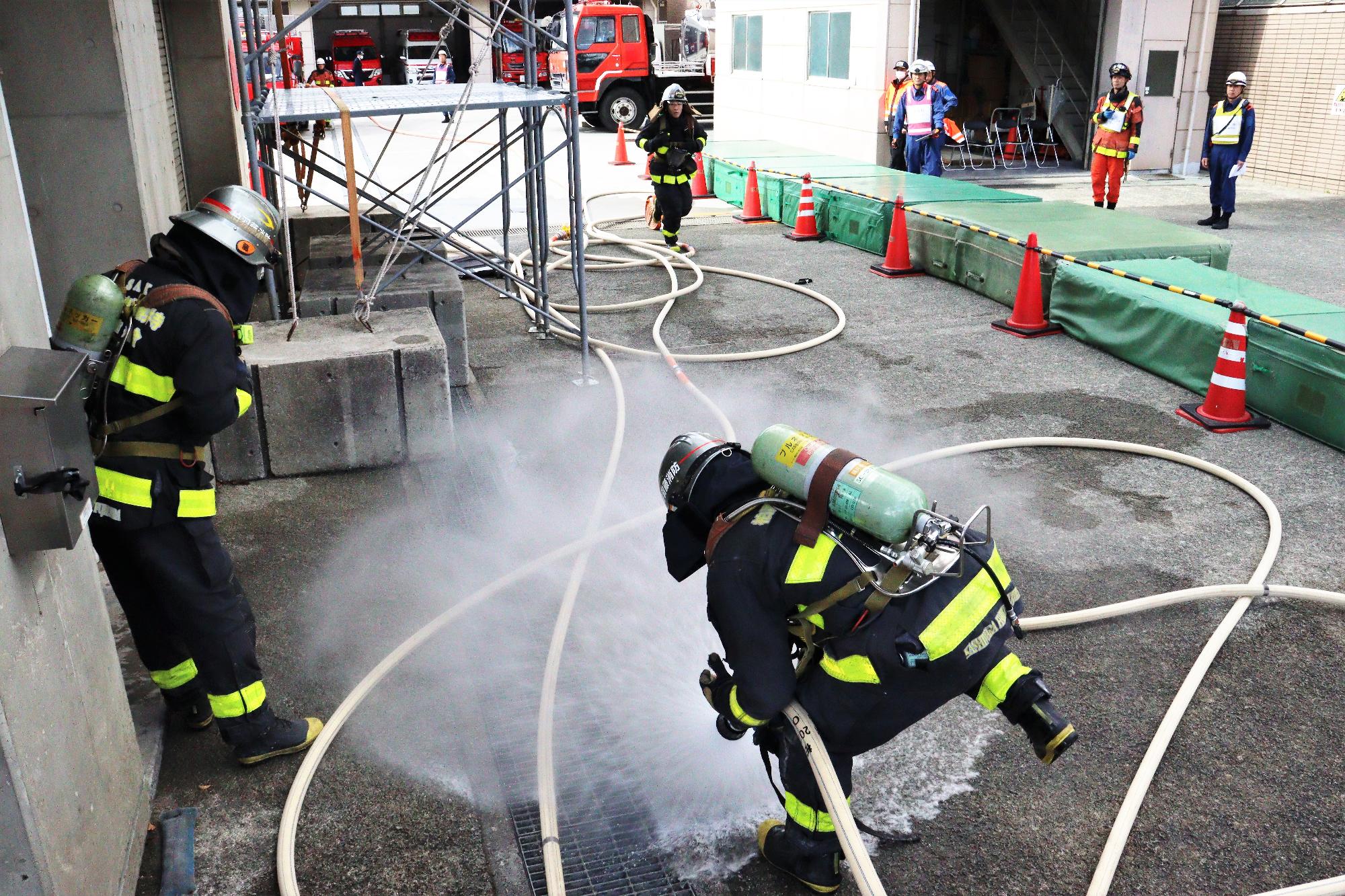 玄関の前で隊員が消防ホースに水を通してホース内に充満させている様子