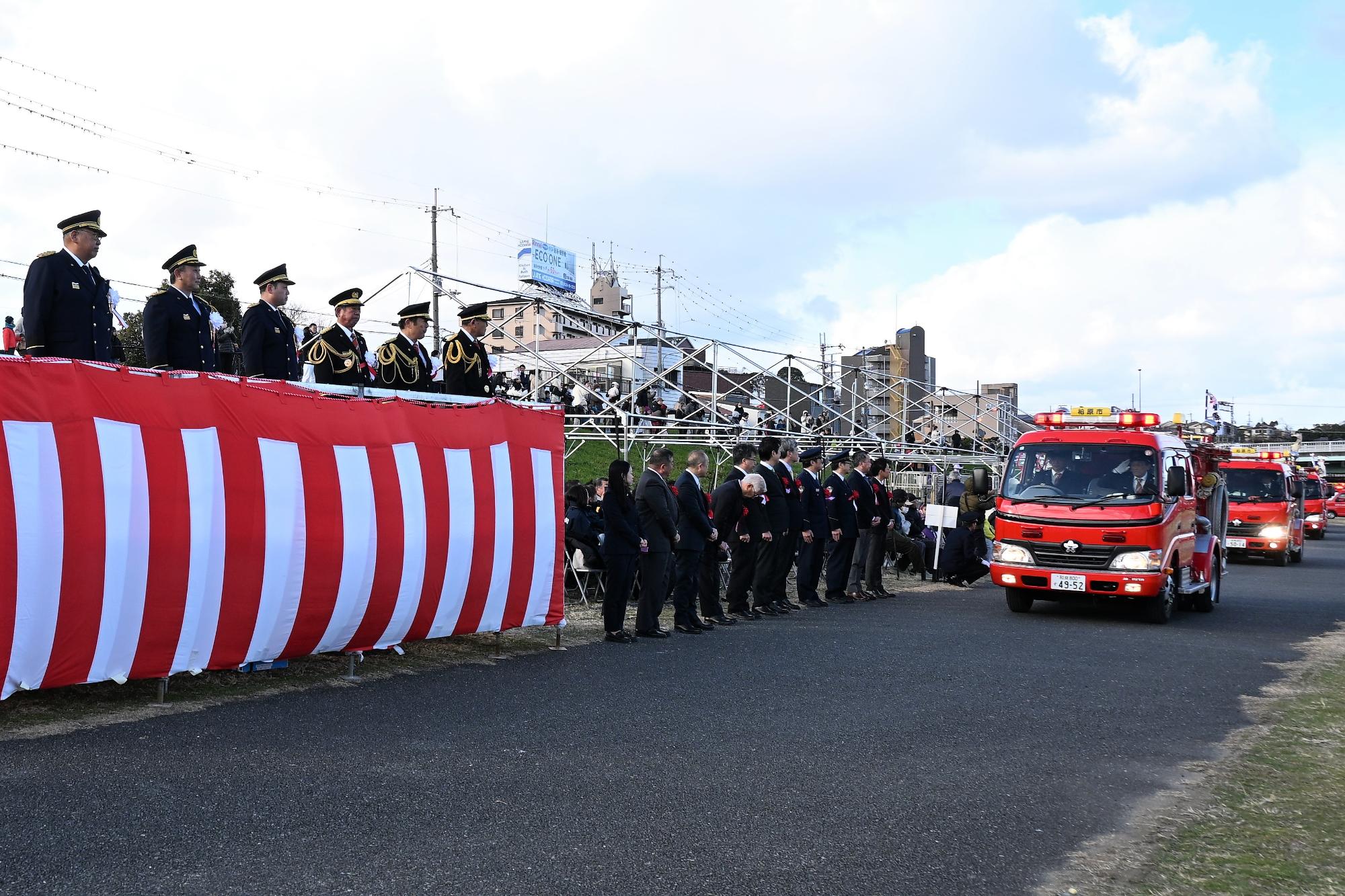 消防団の消防車が連なる行進の様子