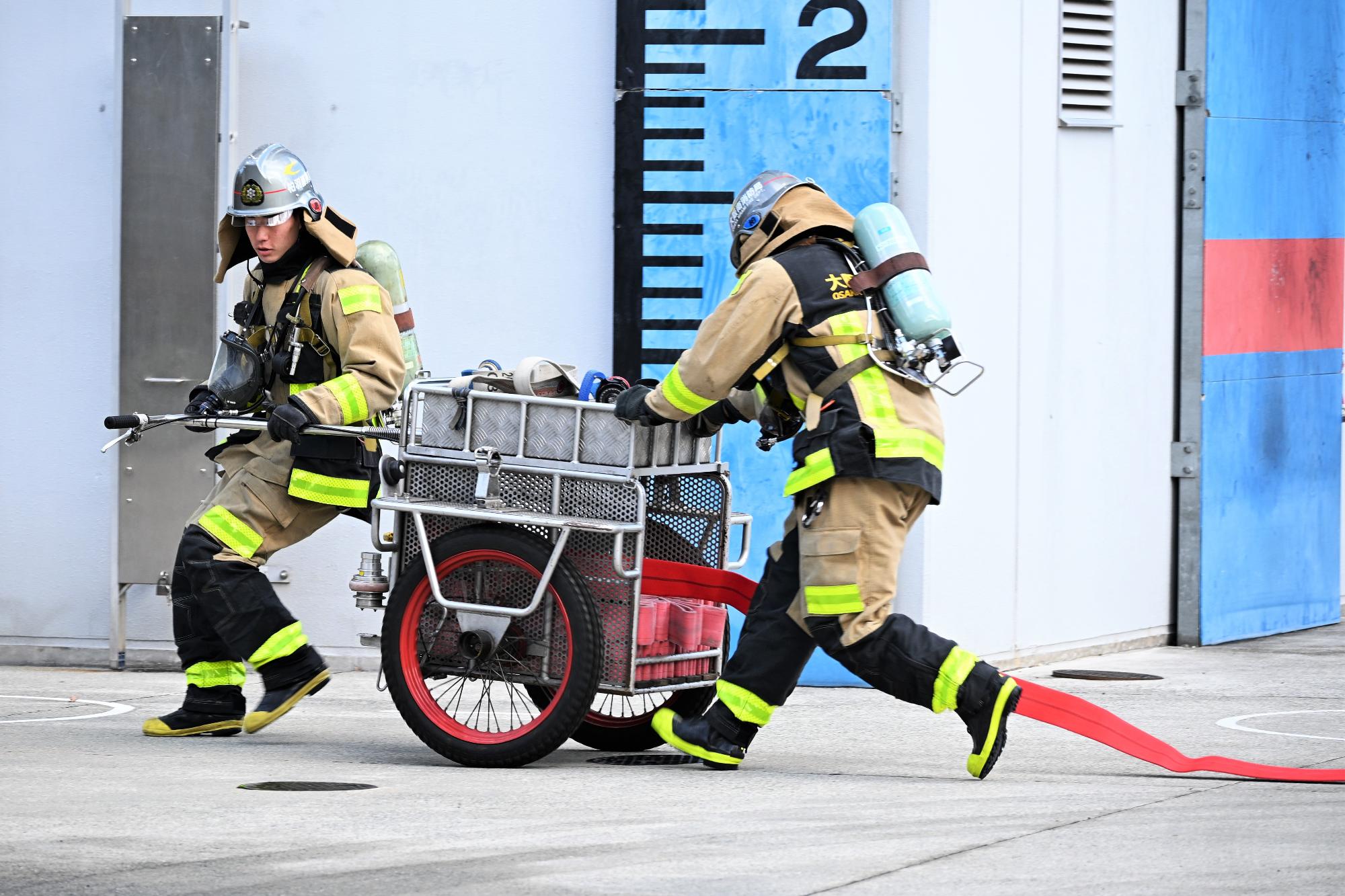 ホースカーを使用して消防ホースを延長する消防隊員の様子