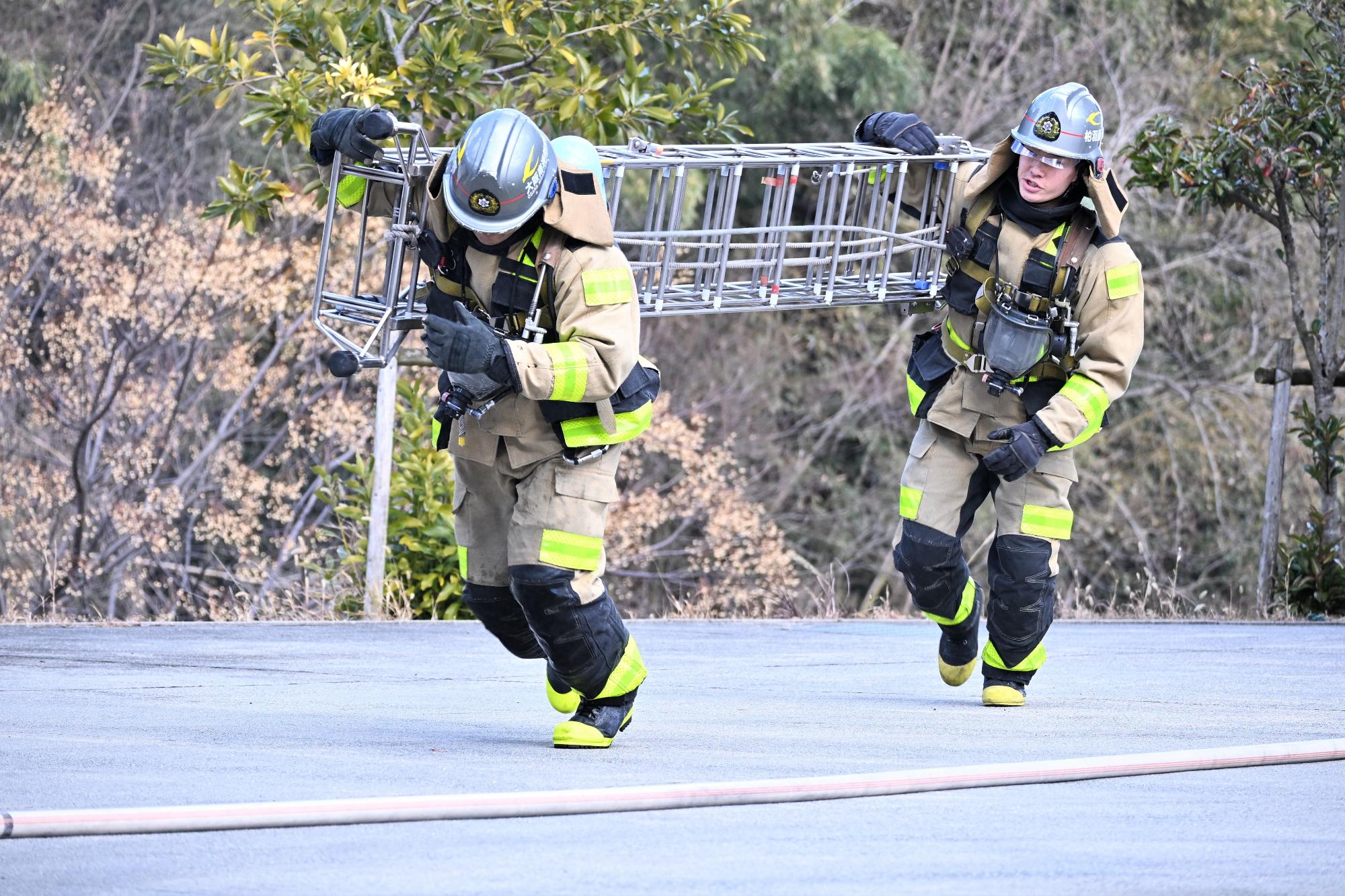 三連梯子を搬送する消防隊員の様子
