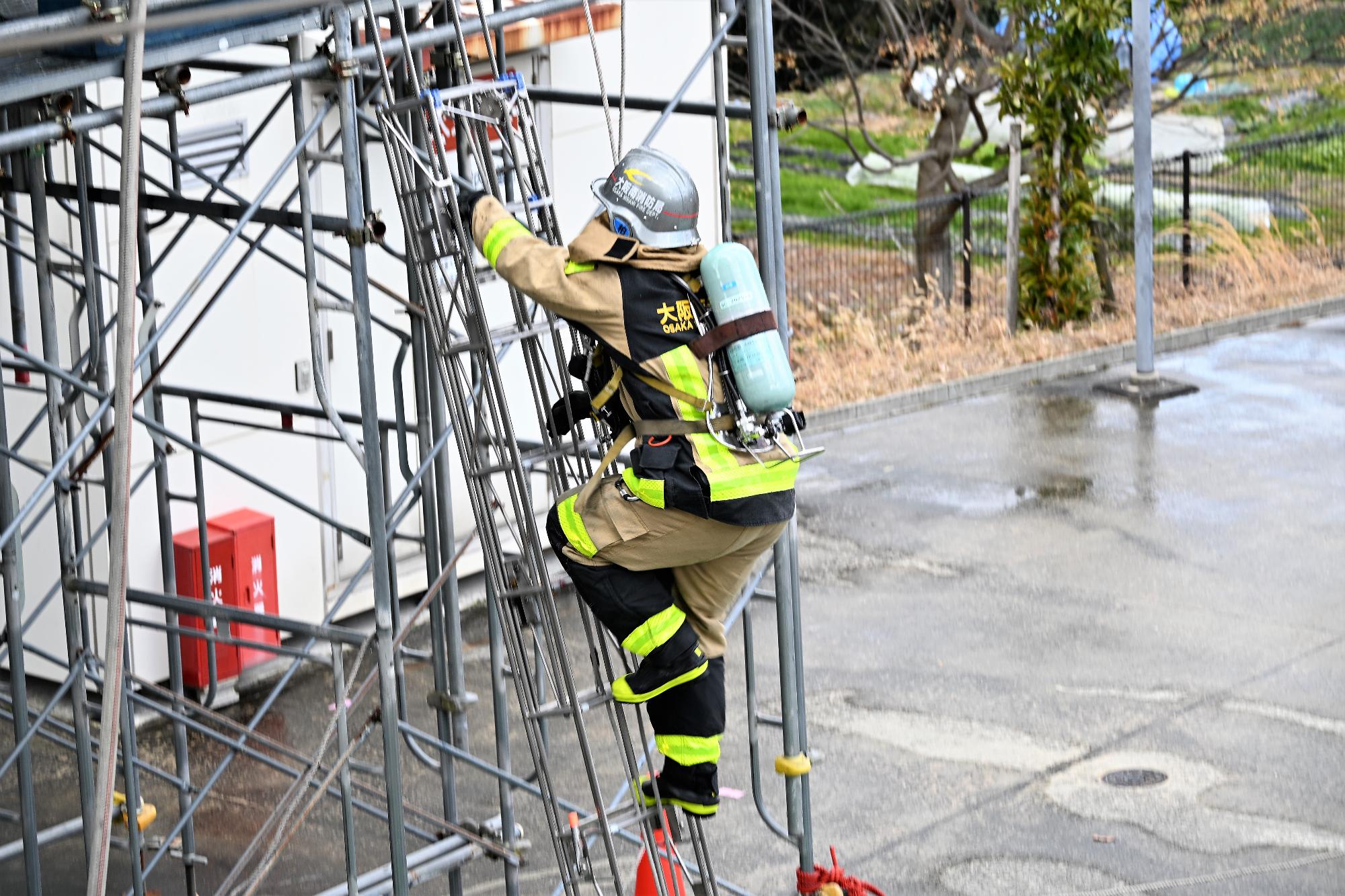 三連梯子を登って2階へ進入する消防隊員の様子