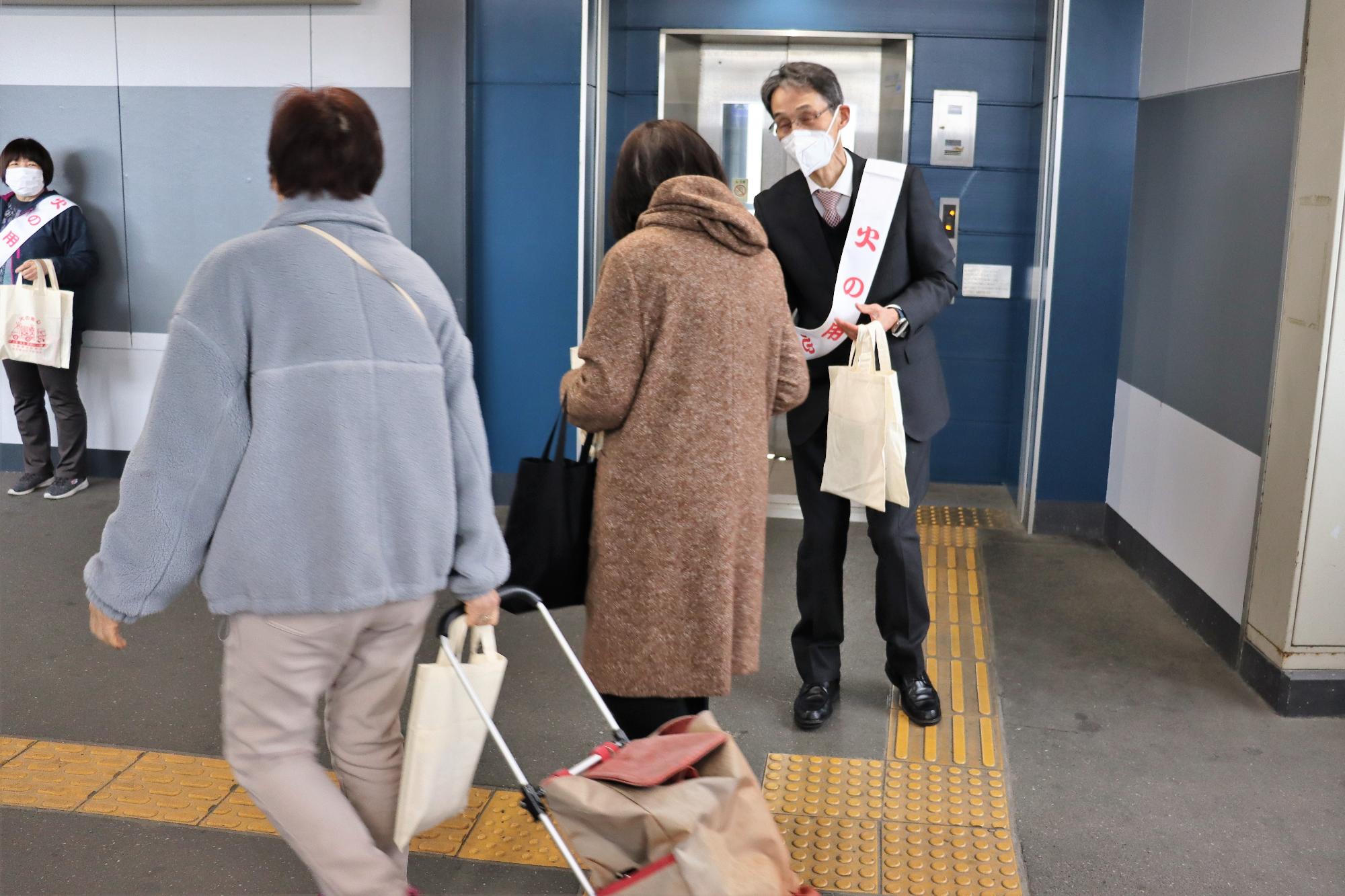 火災予防協会長が配布物を通行人に配布する様子