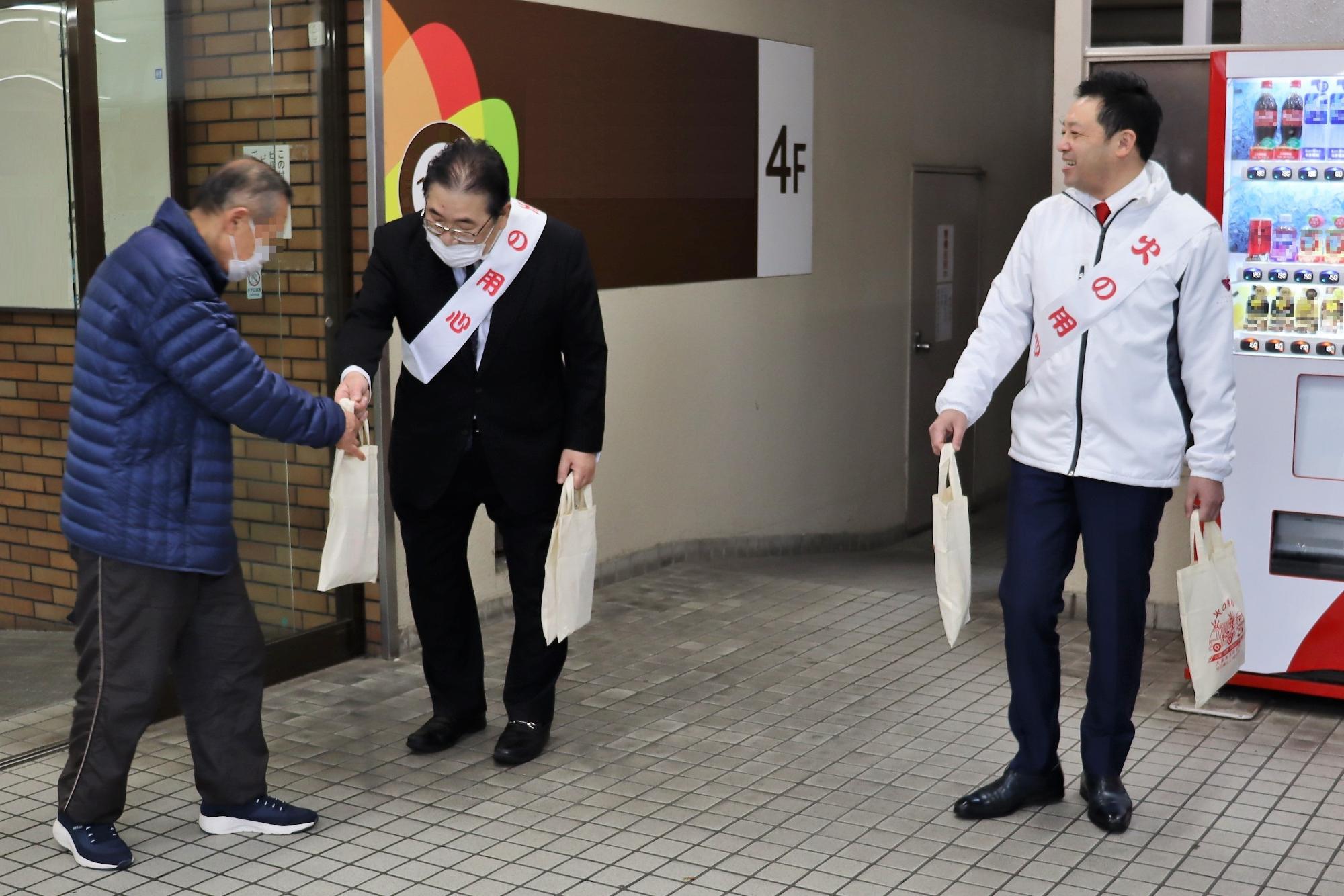柏原市長が配布物を通行人に配布する様子