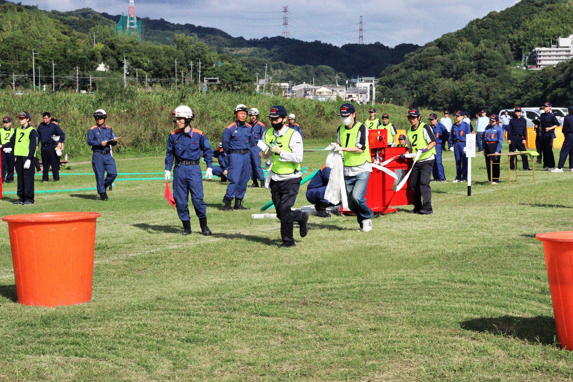 隊員3名が屋内消火栓から協力して消防ホースを取り出し延ばしている風景