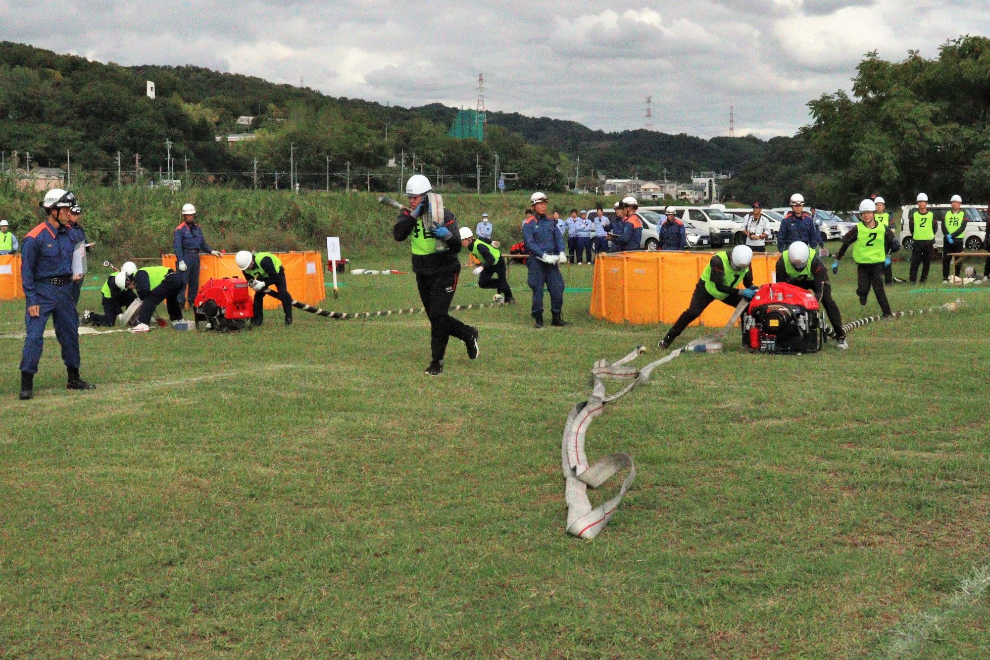小型ポンプから消防ホースを延ばし隊員が消防ホースを搬送している風景