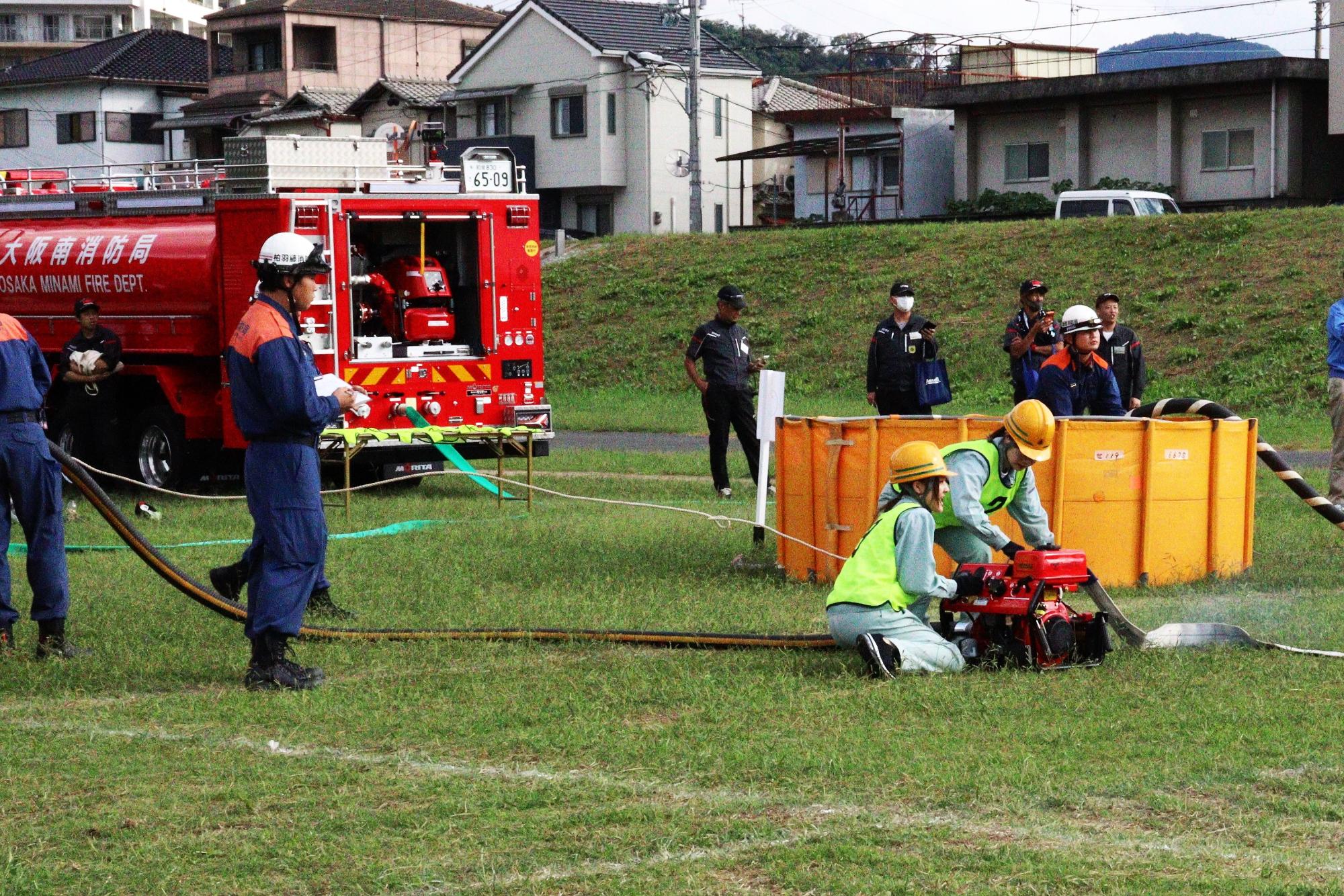 小型ポンプから消防ホースへ送水操作をしている風景