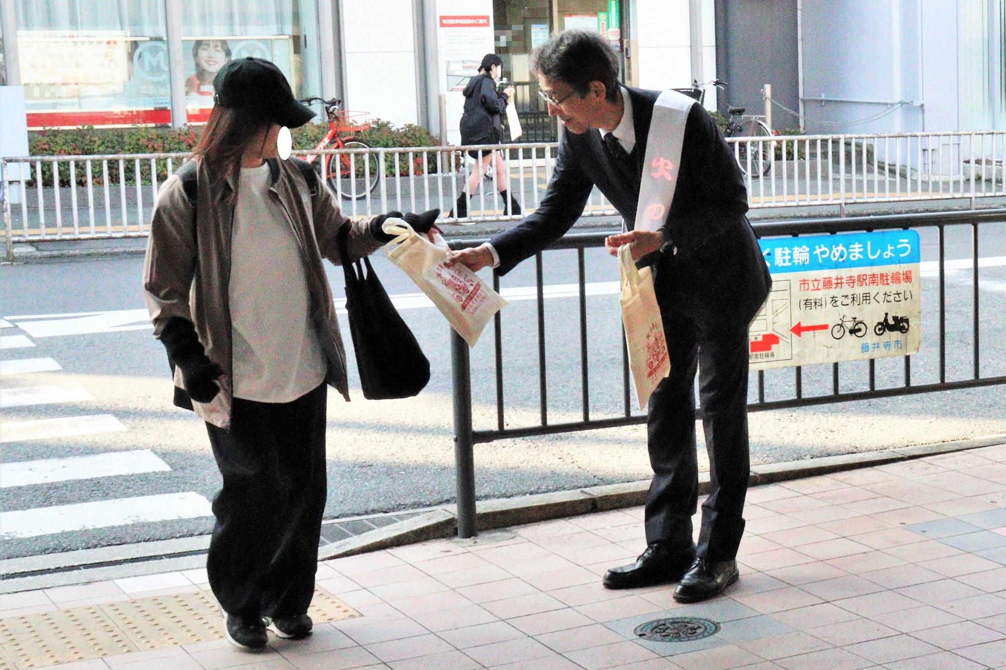 藤井寺駅前にて火災予防協会長による火災予防啓発グッズの配布の様子