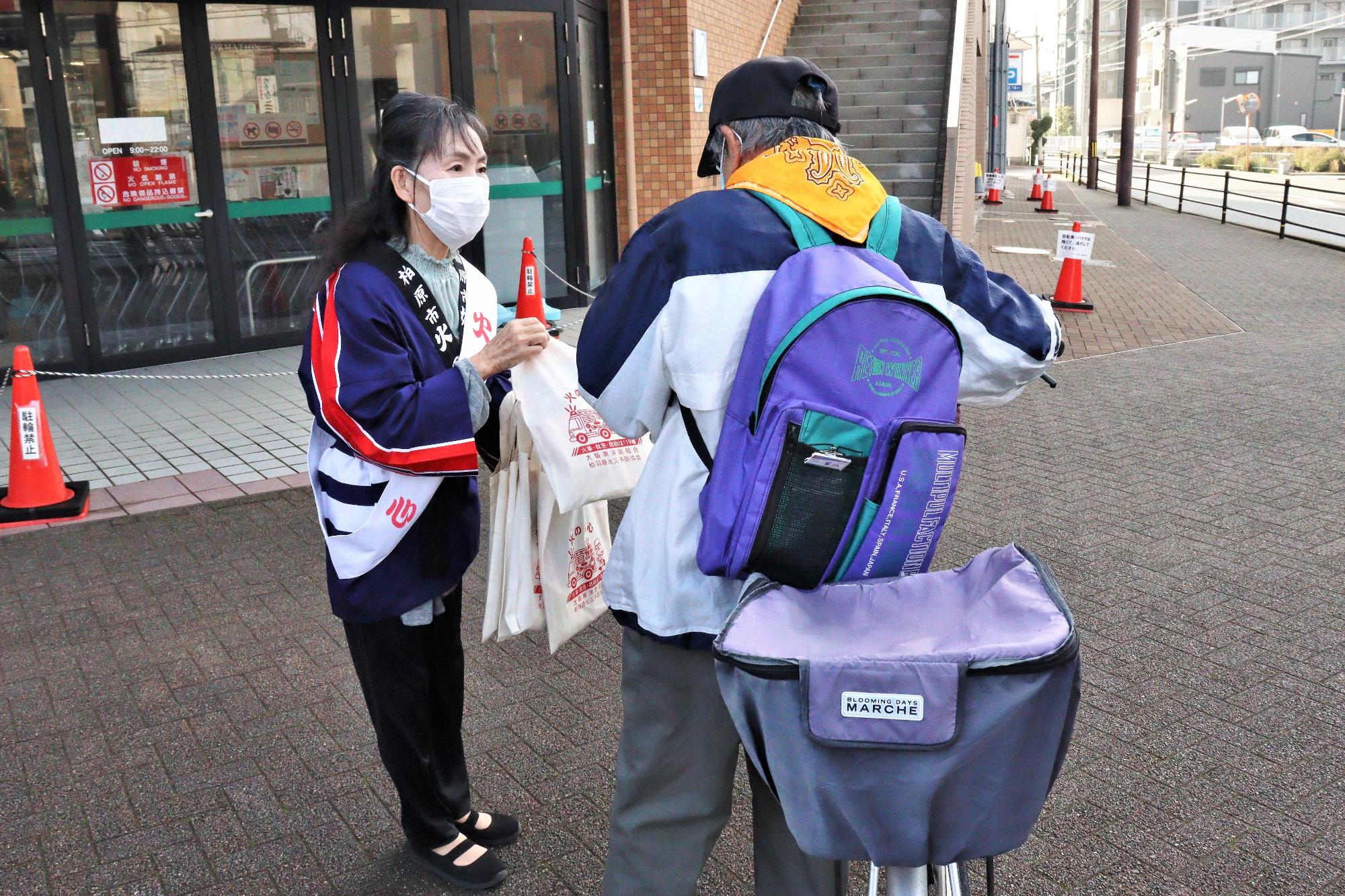 商業施設の前にて柏原市婦人防火クラブ員による火災予防啓発グッズの配布の様子
